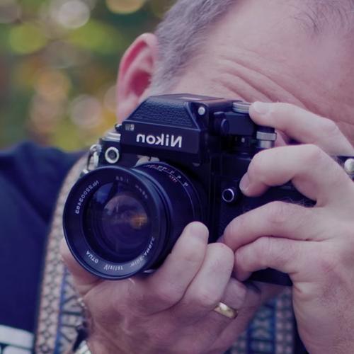 Man looking through a DSLR camera.